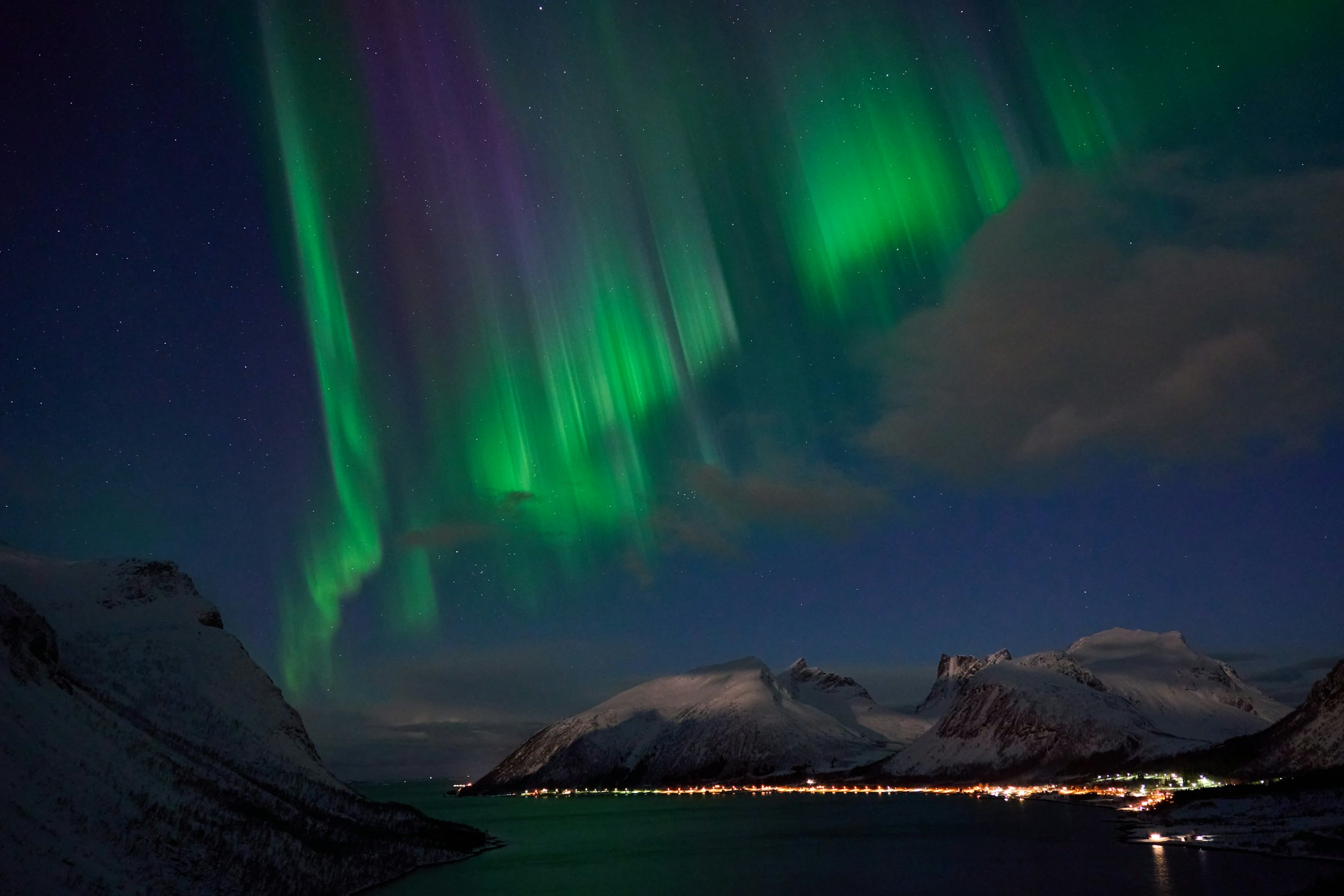 Green and violet aurora borealis filling the sky above a lake